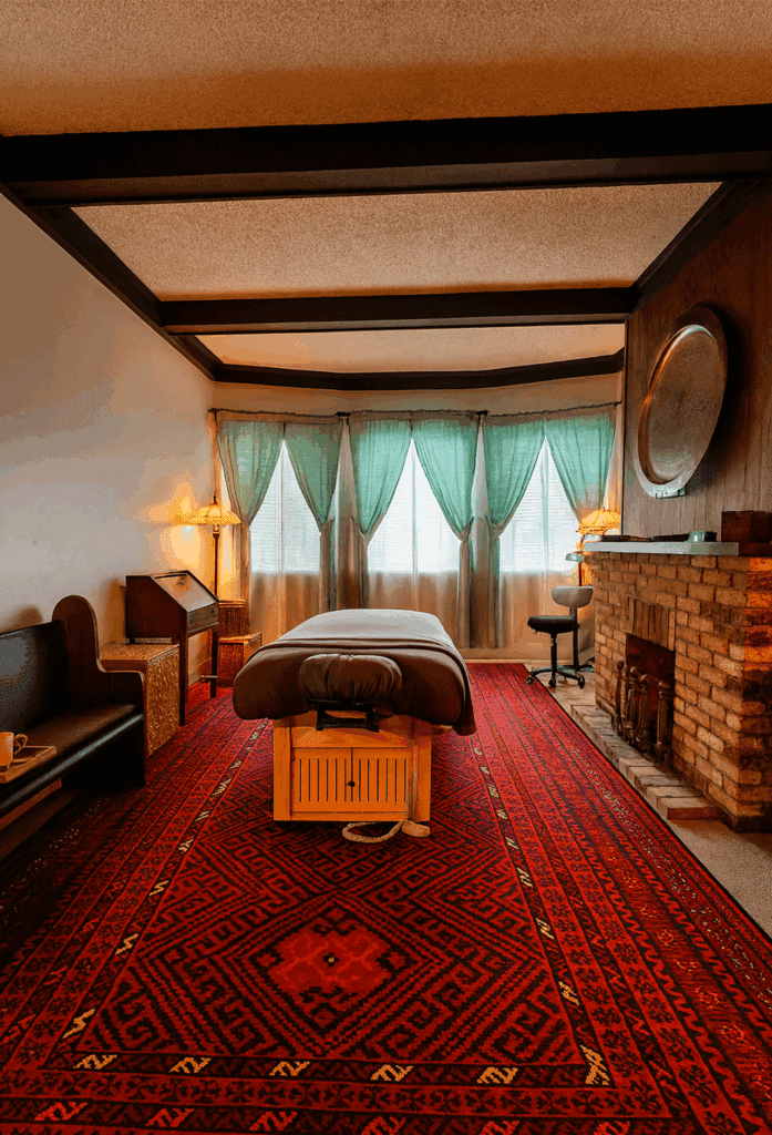 Spacious massage room at Massage Grotto SF featuring a treatment table, decorative rug, and natural light.
