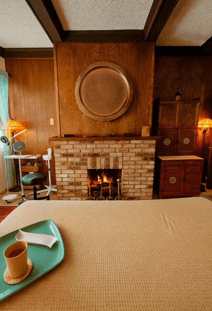 Massage room at Massage Grotto SF with a lit fireplace and tray on the treatment table.